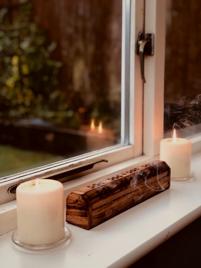 Foto de velas com incensário, saindo fumaça de dentro, no meio.